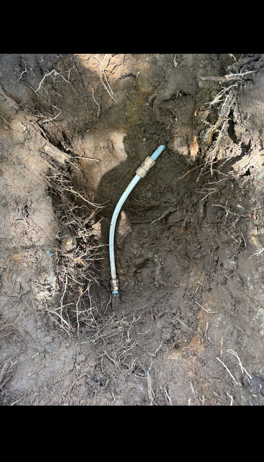 Trenchless pipe replacement access point exposing a blue polyethylene water line in Vancouver