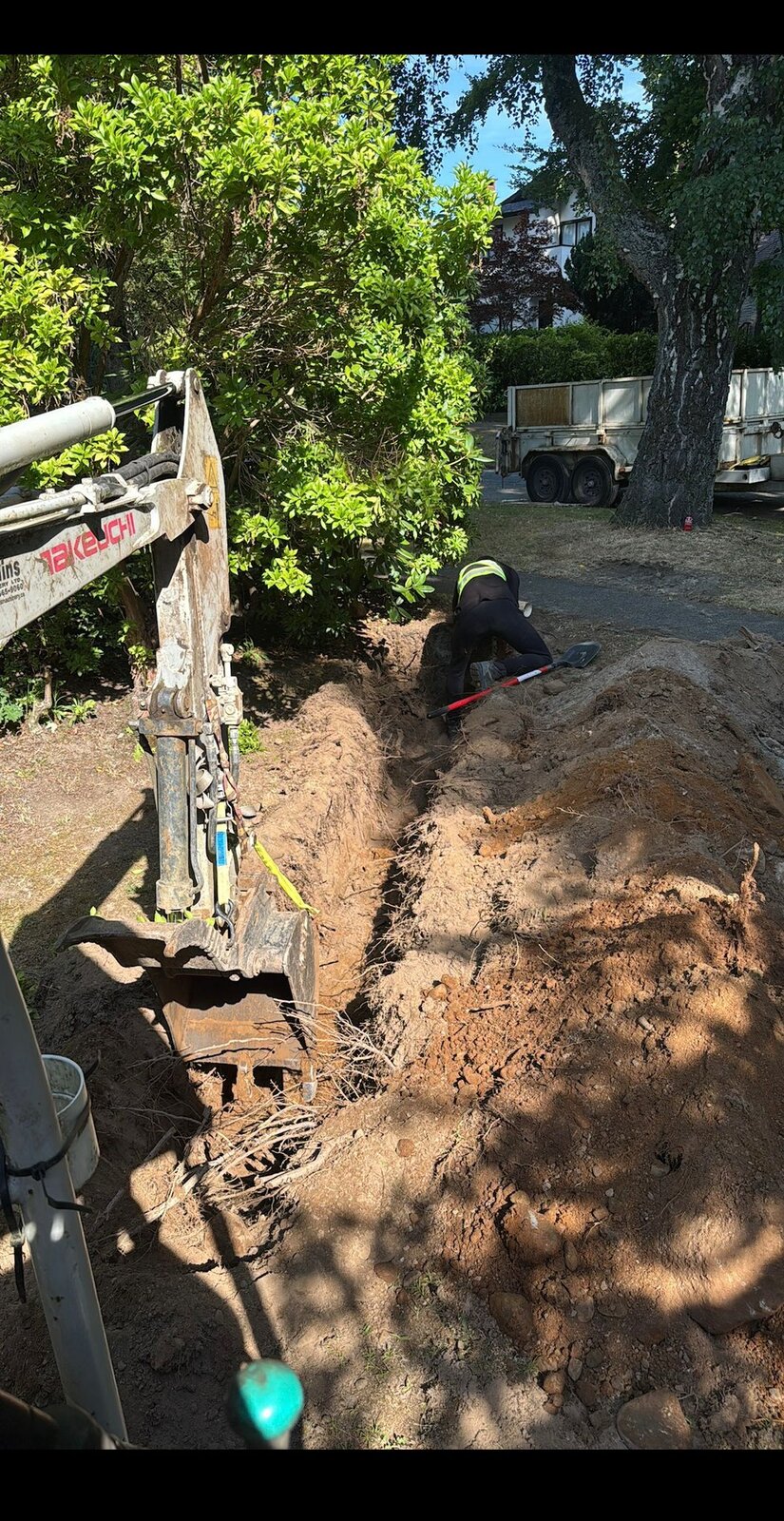 Mini-excavator digging trench for water main replacement at a Vancouver home
